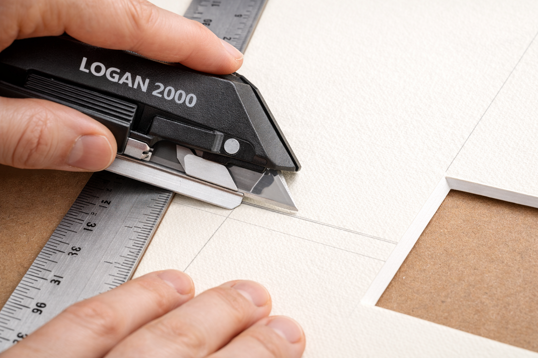 Cutting mat board with beveled edge using mat cutter tool showing proper 45-degree angle technique